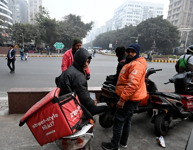 Gig workers rest during a nationwide strike at Connaught Place on December 31, 2025 in New Delhi, India. Gig workers are striking on New Year's Eve, demanding better pay, social security, and an end to 10-minute delivery mandates due to safety concerns and stress. While the strike aimed to disrupt high-demand New Year's Eve services, the overall impact was mitigated by aggressive counter-measures from delivery platforms. - Source: IMAGO / Hindustan Times