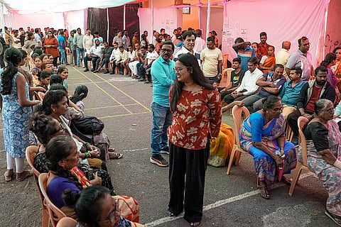 People wait outside a polling booth before casting their votes in the civic polls, in Mumbai. 