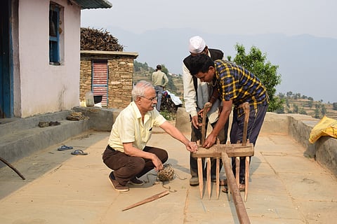 Bharat Bisht works with a farmer to improve a traditional agricultural tool