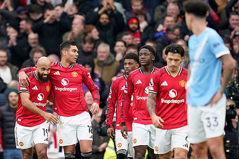 Manchester United's Bryan Mbeumo, left, celebrates with teammates after scoring his side's opening goal during the English Premier League soccer match between Manchester United and Manchester City in Manchester, England.