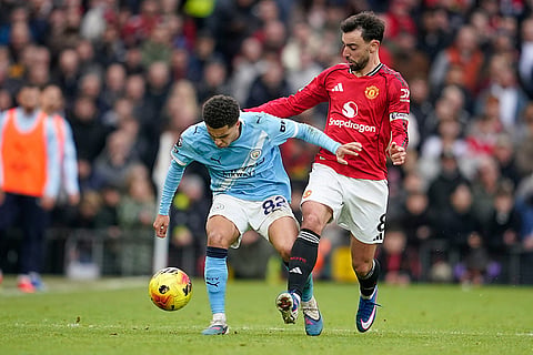 Manchester United's Bruno Fernandes, right, challenges for the ball with Manchester City's Rico Lewis during the English Premier League soccer match between Manchester United and Manchester City in Manchester, England.