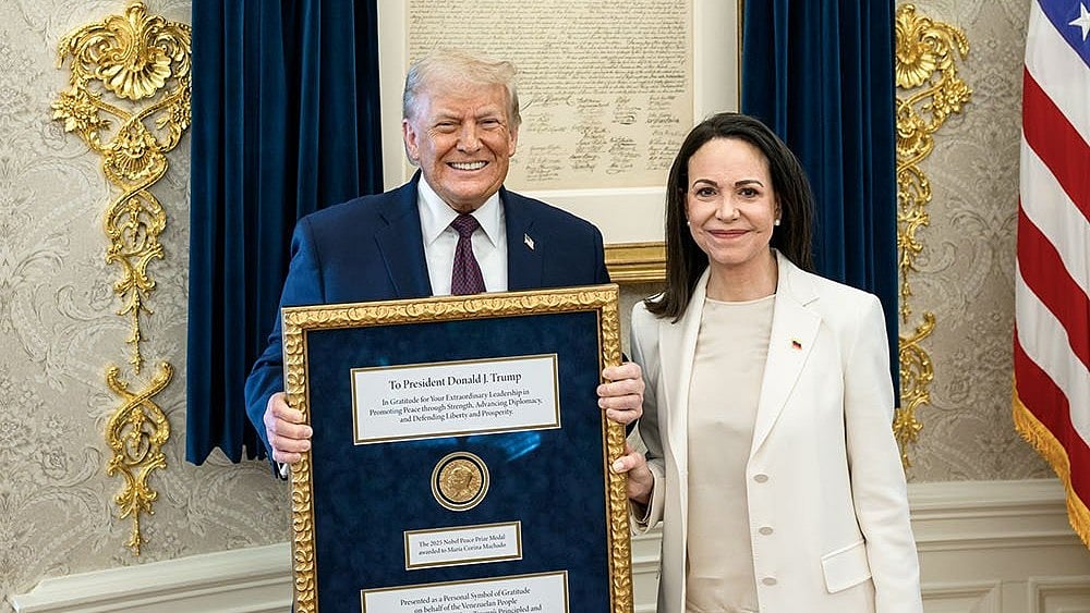 Venezuelan opposition leader María Corina Machado presents her Nobel Peace Prize to US President Donald Trump during a meeting at the Oval Office, in Washington, DC. Machado, who has on previous occasions said that she would give her Nobel prize to Trump, met the American President in the White House Thursday, a closely-watched meeting that came days after the US carried out a military strike in Venezuela and captured its leader Nicolás Maduro.  - | Photo: @WhiteHouse/X via PTI 