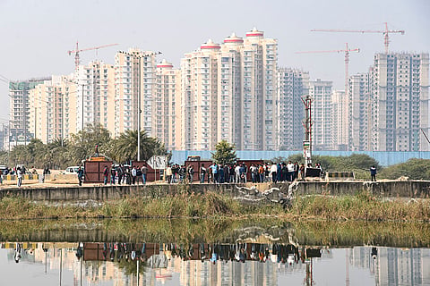 People gather near a water-filled pit at a construction site following the death of a 27-year-old engineer who drowned, in Noida.