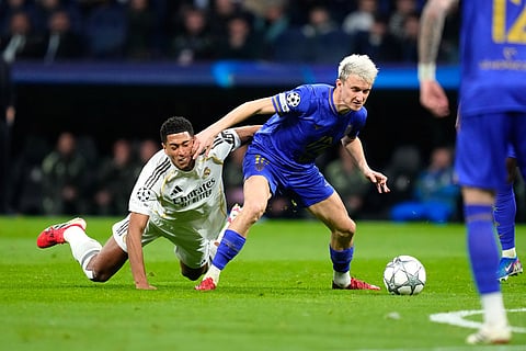 Monaco's Aleksandr Golovin fights for the ball against Real Madrid's Jude Bellingham during the Champions League opening phase soccer match between Real Madrid and Monaco in Madrid.