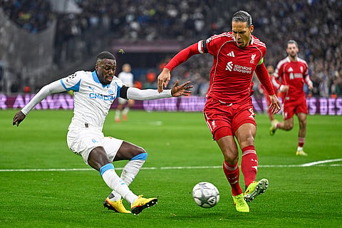 Liverpool's Virgil van Dijk kicks the ball ahead of Marseille's Timothy Weah, left, during the Champions League opening phase soccer match between Marseille and Liverpool in Marseille, France.