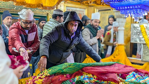 A Devotee offering a chadar on the saint's tomb.
