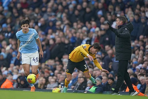 Manchester City's Abdukodir Khusanov, left vies for the ball with Wolverhampton Wanderers' Hugo Bueno during the English Premier League soccer match between Manchester City and Wolverhampton Wanderers in Manchester, England.