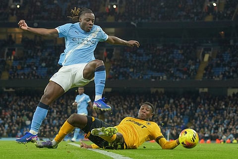 Manchester City's Jeremy Doku, left is tackled by Wolverhampton Wanderers' Yerson Mosquera during the English Premier League soccer match between Manchester City and Wolverhampton Wanderers in Manchester, England.