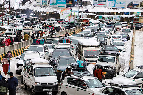 Vehicles remain stuck in a traffic jam as heavy snowfall chokes highways and roads, leaving tourists stranded in Manali.