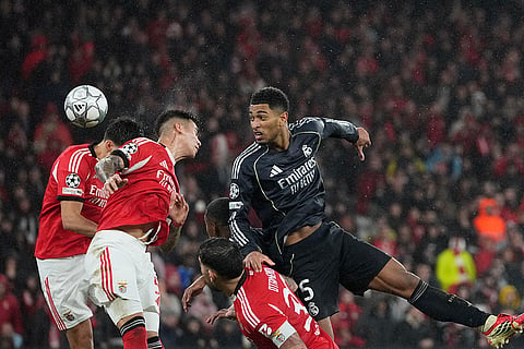 Real Madrid's Jude Bellingham, right, attempts a header at goal during a Champions League opening phase soccer match between Benfica and Real Madrid, in Lisbon.