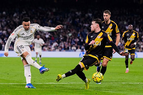 Real Madrid's Kylian Mbappe, left, tries a shot during the Spanish La Liga soccer match between Real Madrid and Rayo Vallecano in Madrid, Spain.