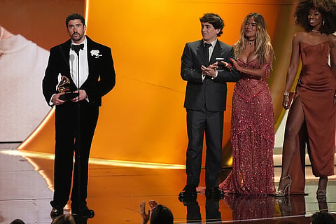 Bad Bunny accepts the award for best música urbana album for "Debí Tirar Más Fotos" during the 68th annual Grammy Awards  in Los Angeles. Marcello Hernandez, center, and Karol G look on from right.