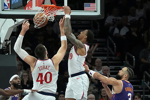 Los Angeles Clippers forward John Collins, second from right, dunks as Phoenix Suns forward Royce O'Neale, left, Clippers center Ivica Zubac (40) and Suns forward Dillon Brooks (3) look on during the first half of an NBA basketball game in Phoenix. 