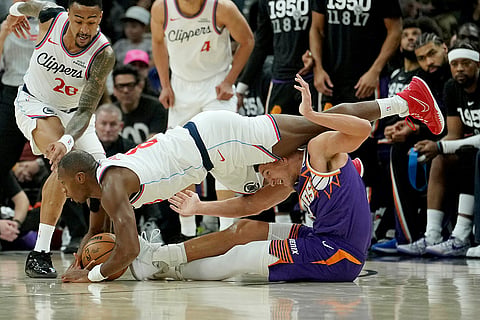Los Angeles Clippers guard Kris Dunn, left, battles with Phoenix Suns guard Grayson Allen, right, for a loose ball as Clippers forward John Collins (20) looks for the ball during the first half of an NBA basketball game in Phoenix. 