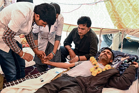A doctor checks an agitator during an indefinite hunger strike by members of the Bishnoi community, demanding a tree protection bill in the ongoing Assembly session and a complete ban on cutting of khejri trees, near a Bishnoi Dharamshala, in Bikaner, Rajasthan.
