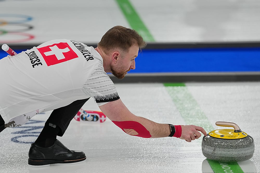 | Photo: AP/Misper Apawu : Switzerland's Yannick Schwaller competes during the mixed doubles round robin phase of the curling competition against Estonia at the 2026 Winter Olympics, in Cortina d'Ampezzo, Italy.