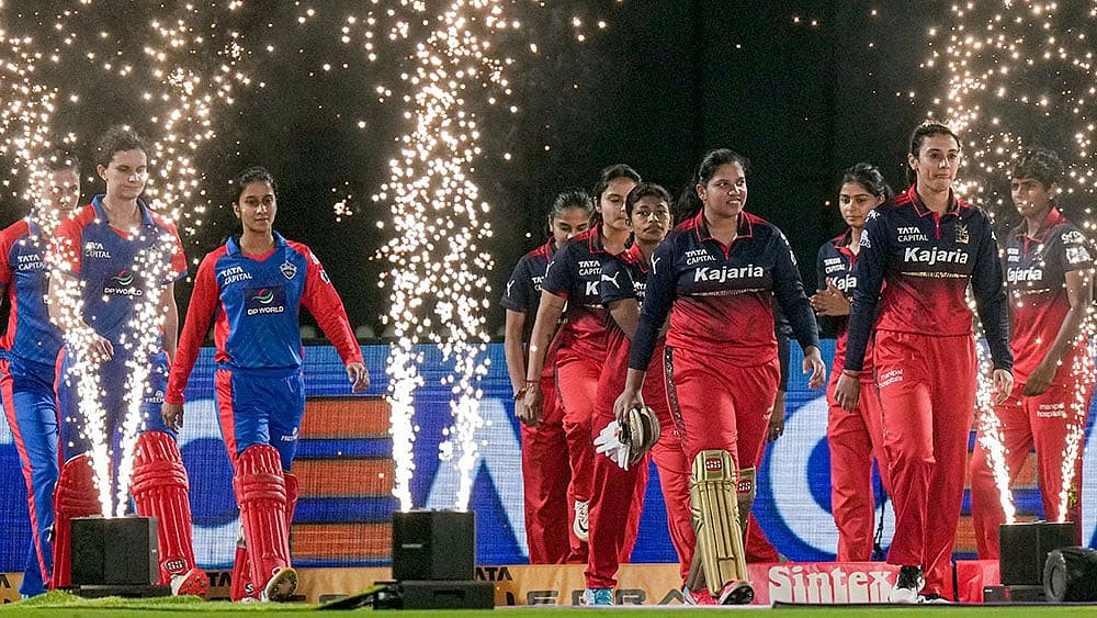 | Photo: PTI/Kunal Patil : Delhi Capitals' captain Jemimah Rodrigues, in blue, and Royal Challengers Bengaluru's captain Smriti Mandhana with their respective teammates enter the field.