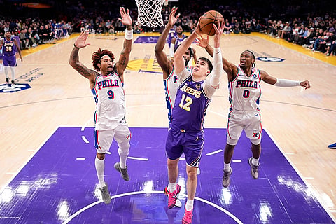 Los Angeles Lakers forward Jake LaRavia, second from right, shoots as Philadelphia 76ers guard Kelly Oubre Jr., left, center Joel Embiid, second from lef and guard Tyrese Maxey defend during the first half of an NBA basketball game in Los Angeles.