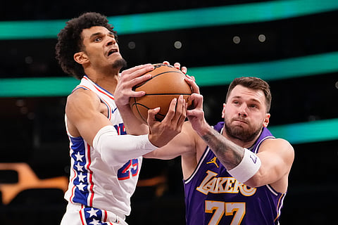 Philadelphia 76ers forward Dominick Barlow, left, and Los Angeles Lakers guard Luka Doncic reach for a rebound during the first half of an NBA basketball game in Los Angeles.