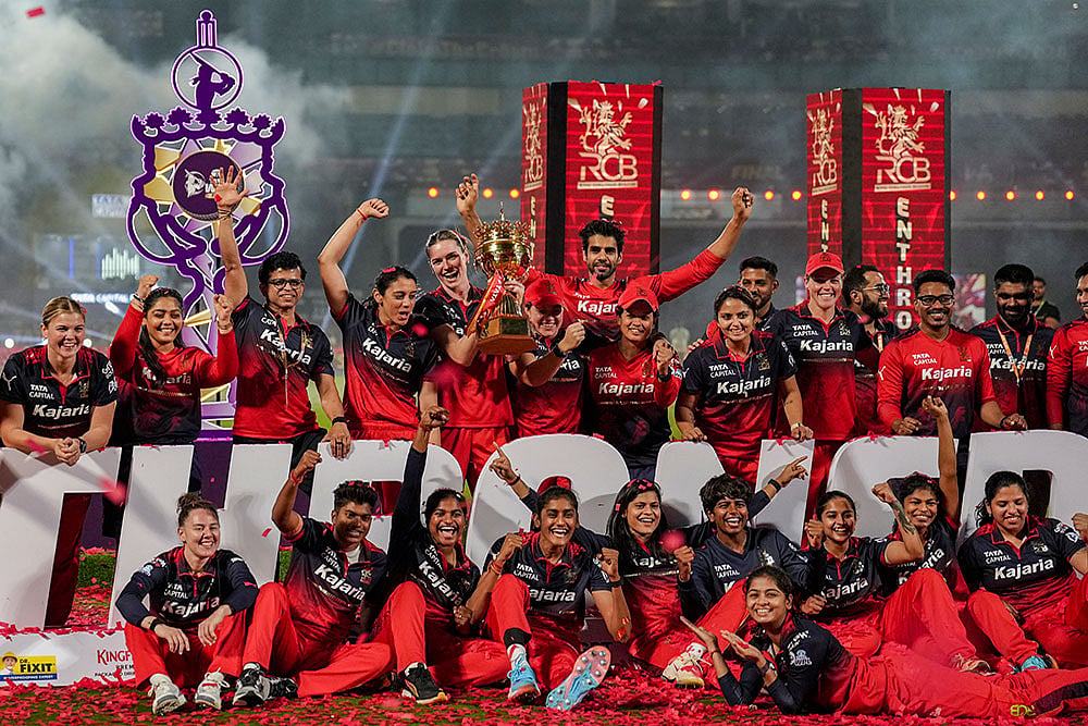 | Photo: PTI/Kunal Patil : Royal Challengers Bengaluru's players celebrate with the trophy after winning the Women's Premier League (WPL) 2026 final T20 cricket match against Delhi Capitals, at Baroda Cricket Association Stadium, Kotambi in Vadodara, Gujarat.