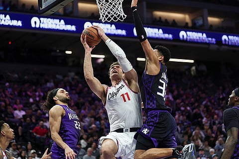 Los Angeles Clippers center Brook Lopez (11) gets blocked by Sacramento Kings center Dylan Cardwell, right, as he goes up for a dunk during the second half of an NBA basketball game in Sacramento, California.