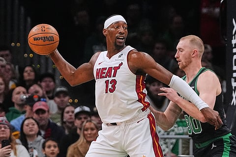 Miami Heat center Bam Adebayo (13) looks to pass the ball while covered by Boston Celtics forward Sam Hauser (30) during the first half of an NBA basketball game in Boston.