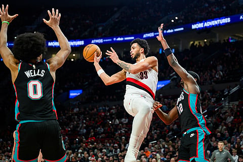 Portland Trail Blazers forward Toumani Camara (33) throws to an open teammate between defense from Memphis Grizzlies forwards Jaylen Wells (0) and Taylor Hendricks (22) in the second half of an NBA basketball game in Portland, Oregon.