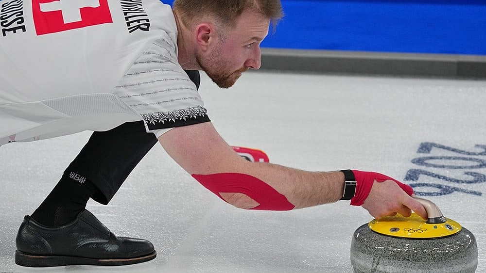 | Photo: AP/Misper Apawu : Switzerland's Yannick Schwaller in action during the mixed doubles round robin phase of the curling competition against Estonia at the 2026 Winter Olympics, in Cortina d'Ampezzo, Italy.