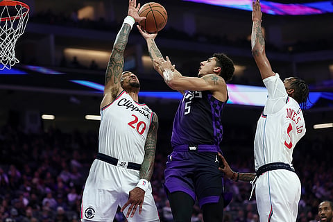 Sacramento Kings guard Nique Clifford, center, goes up to shoot between Los Angeles Clippers forwards John Collins (20) and Derrick Jones Jr., right, during the first half of an NBA basketball game in Sacramento, California.