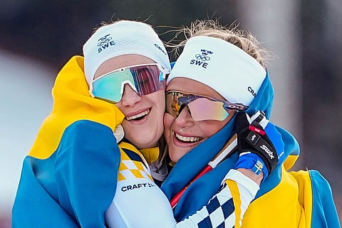Frida Karlsson, right, and Ebba Andersson, both of Sweden, celebrate after finishing first and second in the cross-country skiing women's 10km + 10km skiathlon at the 2026 Winter Olympics, in Tesero, Italy.
