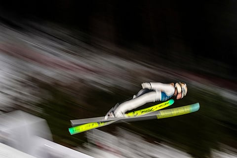 Meghann Wadsak, of Austria, soars through the air during her first round jump of the ski jumping women's normal hill individual, at the 2026 Winter Olympics, in Predazzo, Italy.