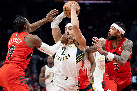 Indiana Pacers guard Andrew Nembhard (2) is double-teamed by Toronto Raptors' Brandon Ingram (3) and R.J. Barrett (9) as he drives to the hoop during first-half NBA basketball game action in Toronto.