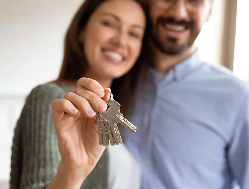 Smiling couple holding up a set of silver house keys