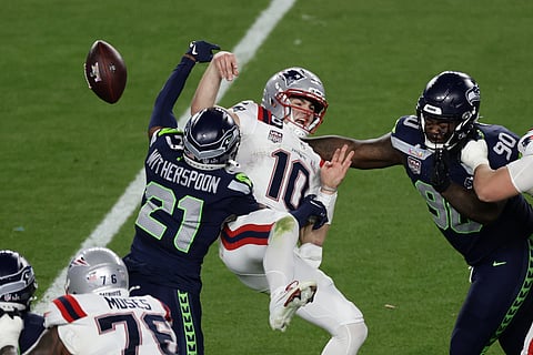 Seattle Seahawks cornerback Devon Witherspoon (21) forces a fumble against New England Patriots quarterback Drake Maye (10) at the NFL Super Bowl 60 game in Santa Clara, California.
