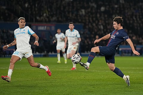 Marseille's Facundo Medina, left, tries to block a shot from PSG's Joao Neves during the French League One soccer match between Paris Saint-Germain and Marseille in Paris.