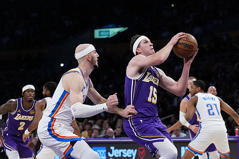 Los Angeles Lakers guard Austin Reaves (15) drives to the basket past Oklahoma City Thunder guard Alex Caruso during the first half of an NBA basketball game in Los Angeles.