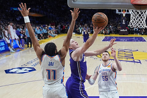 Los Angeles Lakers guard Austin Reaves, center, drives to the basket past Oklahoma City Thunder guard Isaiah Joe during an NBA basketball game in Los Angeles. 