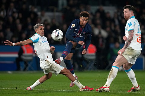 Marseille's Facundo Medina, left, tries to block a shot from PSG's Desire Doue challenge for the ball during the French League One soccer match between Paris Saint-Germain and Marseille in Paris.