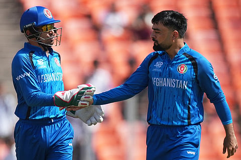 Afghanistan's captain Rashid Khan, right and Mohammad Nabi celebrates the dismissal of South Africa's Quinton de Kock during the T20 World Cup cricket match between Afghanistan and South Africa in Ahmedabad.