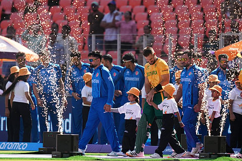 Afghanistan's captain Rashid Khan, and South Africa's captain Aiden Markram, yellow shirt, leads their teams for their national anthem during the T20 World Cup cricket match between Afghanistan and South Africa in Ahmedabad.