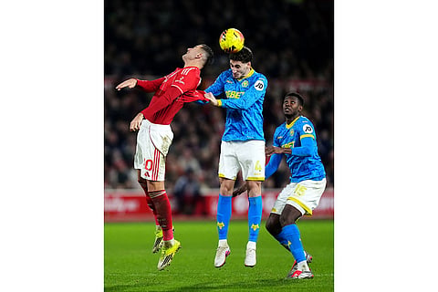 Nottingham Forest's Lorenzo Lucca, left, battles for the ball with Wolverhampton Wanderers' Santiago Bueno, during their English Premier League soccer match, in Nottingham, England.