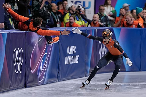 Jens van't Wout of the Netherlands slaps hands with a coach after winning gold during the short track speed skating men's 1000m at the 2026 Winter Olympics, in Milan, Italy.