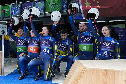 Ukraine's Yulianna Tunytska, Olena Stetskiv, Oleksandra Mokh, Nazarii Kachmar, Ihor Hoi and Andriy Mandziy kneel down during the luge relay competition at the 2026 Winter Olympics, in Cortina d'Ampezzo, Italy.