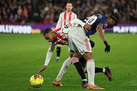 Arsenal's Noni Madueke, right, and Brentford's Dango Ouattara fight for the ball during the English Premier League soccer match between Brentford and Arsenal in London.