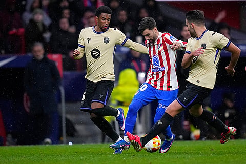 Barcelona's Eric Garcia, right, and Alejandro Balde, left, challenge for the ball with Atletico Madrid's Alex Baena during the Copa del Rey semifinal first leg soccer match between Atletico Madrid and Barcelona in Madrid, Spain.