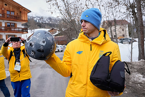 Ukrainian skeleton athlete Vladyslav Heraskevych holds his crash helmet as he stands outside the sliding center at the 2026 Winter Olympics, in Cortina d'Ampezzo, Italy.