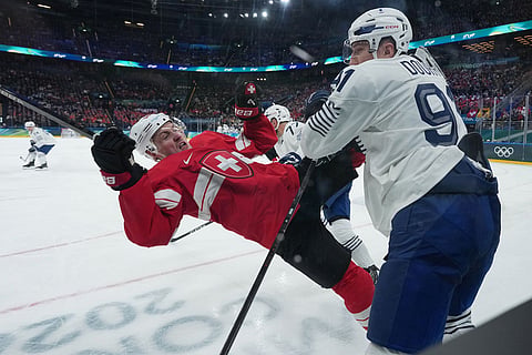 France's Floran Douay, right, checks Switzerland's Dean Kukan during a preliminary round match of men's ice hockey between Switzerland and France at the 2026 Winter Olympics, in Milan, Italy.