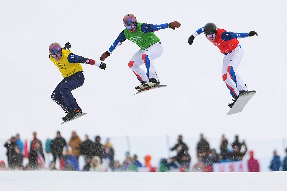 | Photo: AP/Lindsey Wasson : United States' Nathan Pare (13), France's Jonas Chollet (4) and France's Loan Bozzolo (5) compete during the men's snowboard cross finals at the 2026 Winter Olympics, in Livigno, Italy.