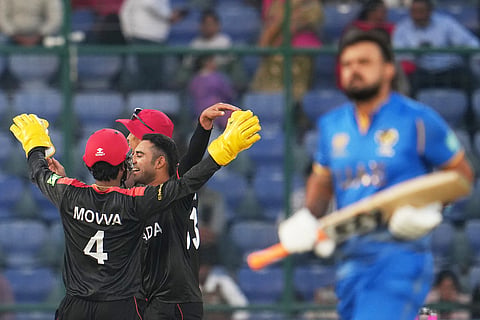 Canada's Saad Bin Zafar, smiling, and Shreyas Movva celebrate the wicket of United Arab Emirates' Mayank Kumar during the T20 World Cup cricket match between Canada and United Arab Emirates in New Delhi.