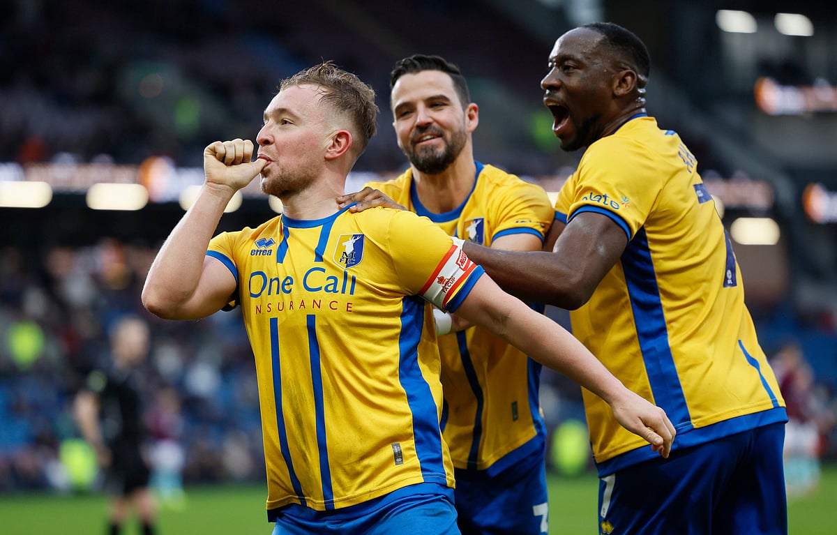 | Photo: PA/Richard Sellers via AP : Mansfield Town's Louis Reed, left, celebrates scoring during the English FA Cup fourth round soccer match between Burnley and Mansfield Town in Burnley, England, Saturday Feb. 14, 2026. 